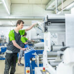 Mitarbeiter bedient GMP-konforme Falzmaschine für pharmazeutische Packungsbeilagen